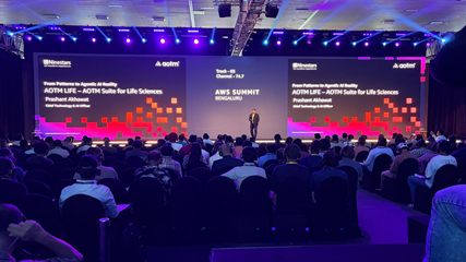 Prashant Akhawat on stage at AWS Summit Bengaluru 2026, beside the &lsquo;From Patterns to Agentic AI Reality &mdash; AOTM LIFE&rsquo; slide naming him Chief Technology & AI Officer.
